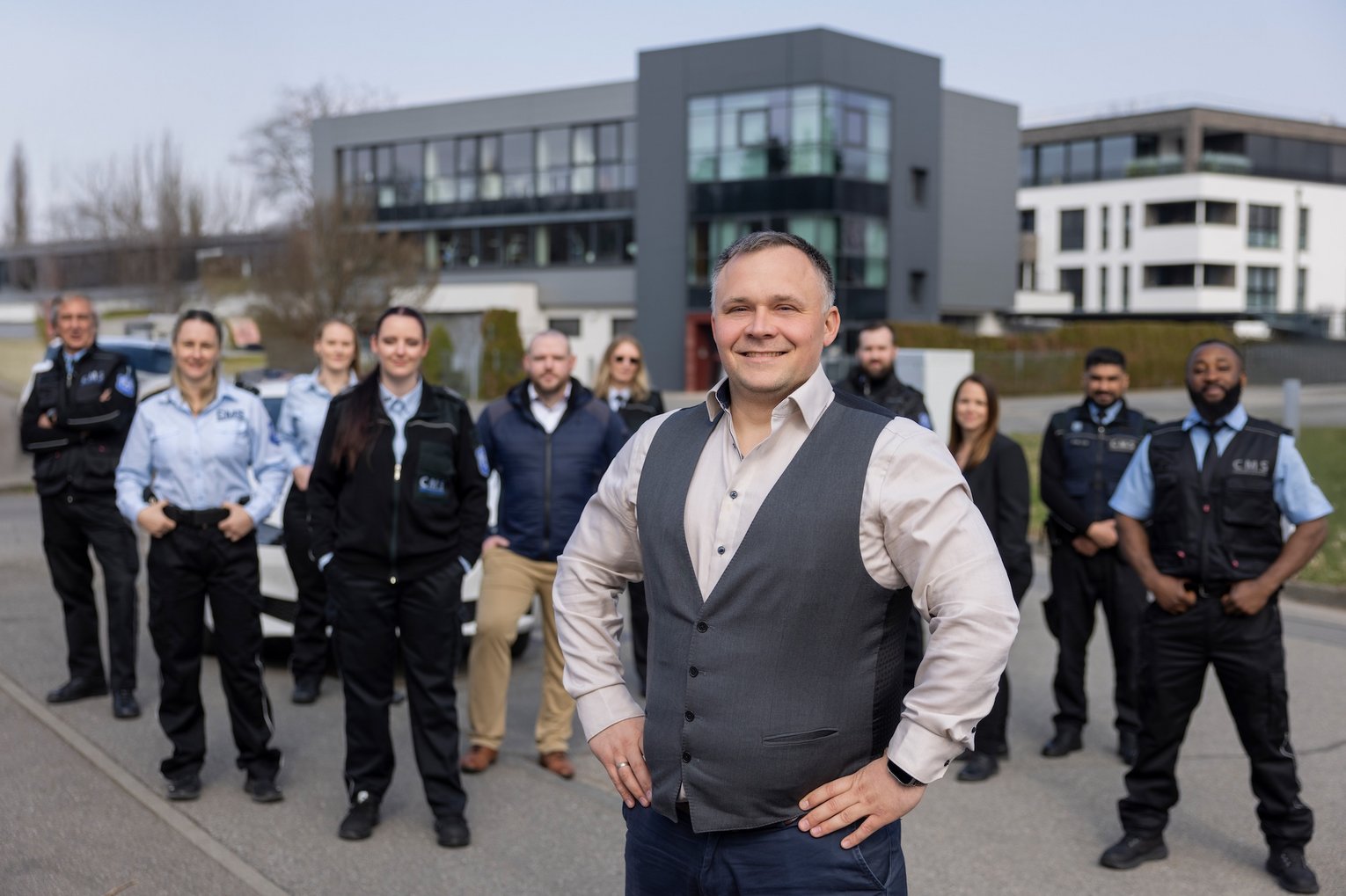 CMS Geschäftsführung mit Sicherheitsteam Geschäftsführer mit Team des CMS Sicherheitsdienstes steht vor modernem Bürogebäude und präsentiert das Unternehmen